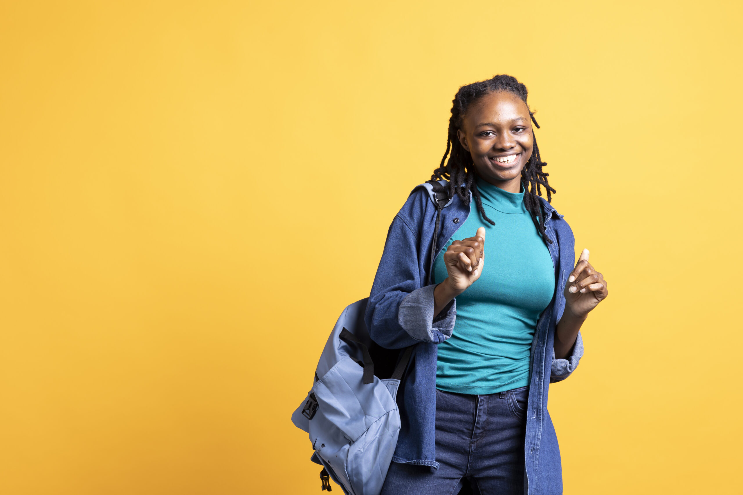 Carefree african american young girl with positive wellbeing, feeling joyful, isolated over studio background. Portrait of pleased woman celebrating free time, doing energic hand gesturing